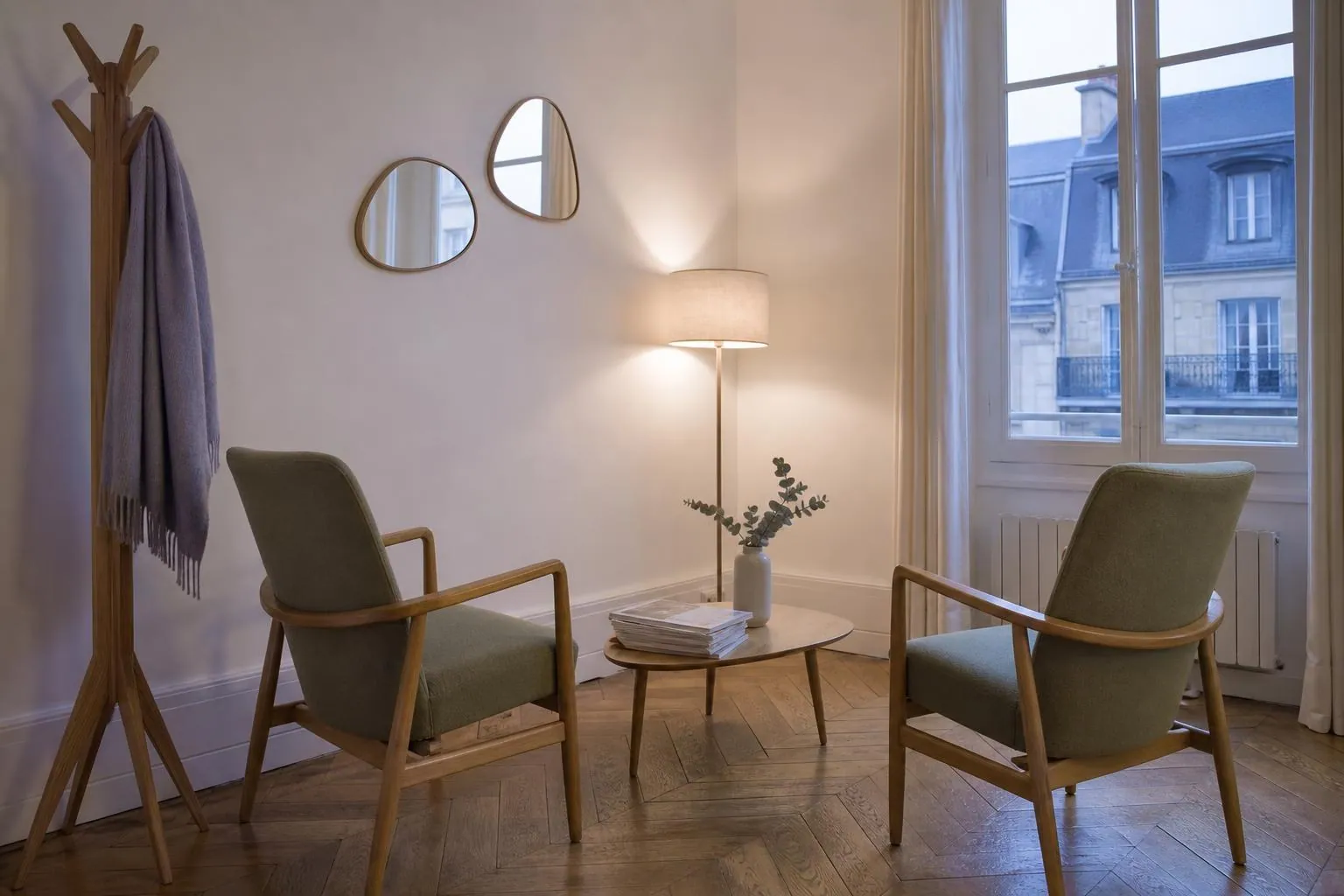 Salle d’attente vide d’un cabinet de psychologue en hiver, deux fauteuils sauge, une plante et un portemanteau