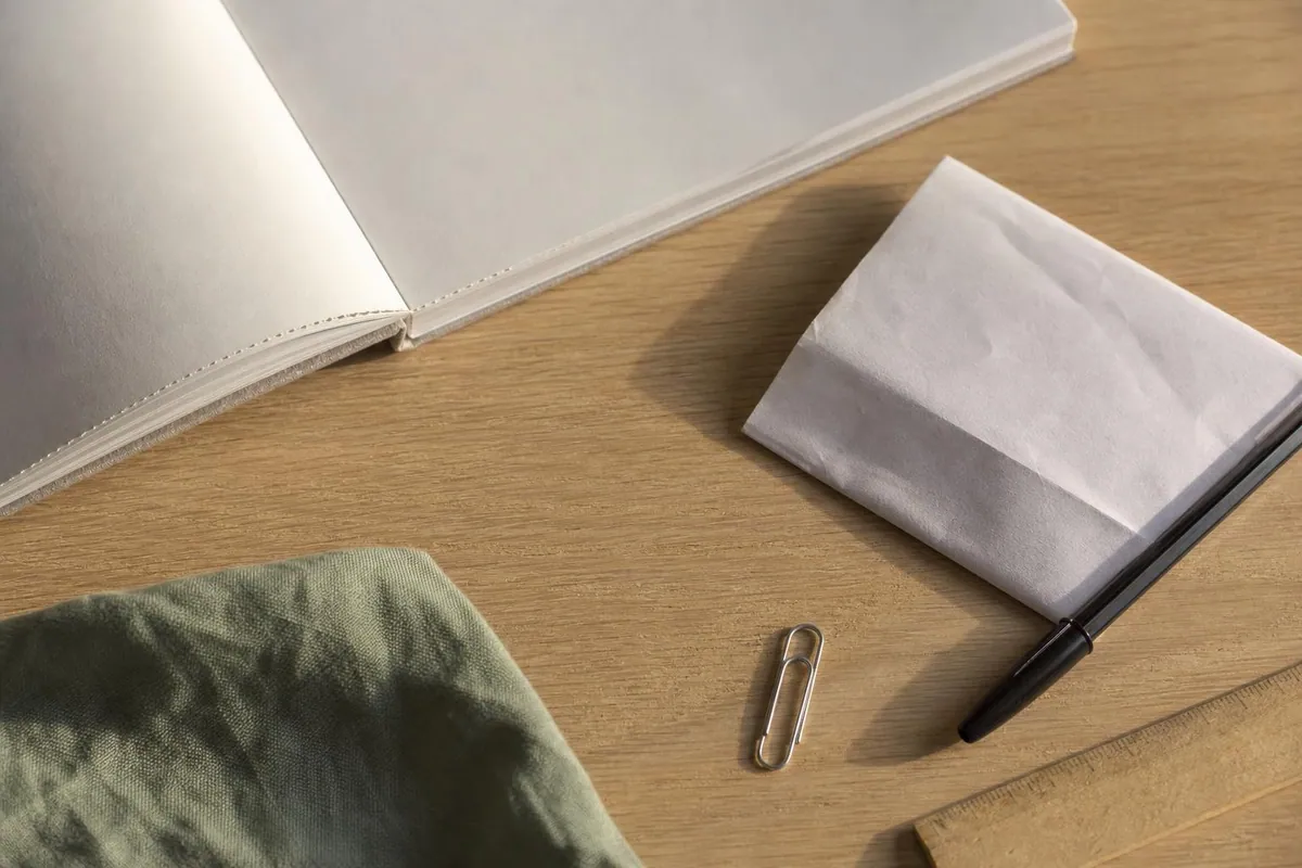 Gros plan de documents administratifs de cabinet posés sur un bois clair, talon de carnet à souche et relevé plié, avec un stylo